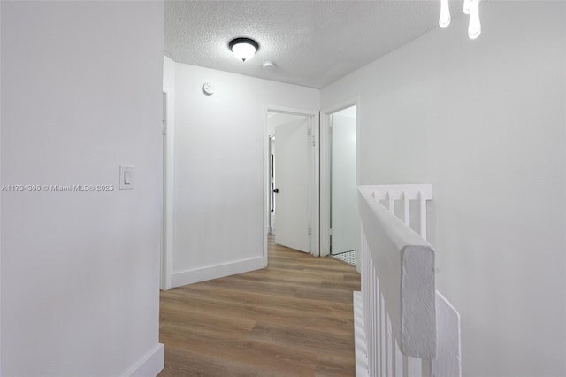 hall with hardwood / wood-style flooring and a textured ceiling