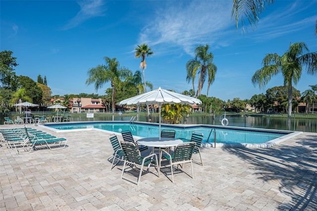 view of pool featuring a water view and a patio