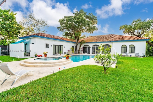 rear view of property with a patio, a yard, and a pool with hot tub