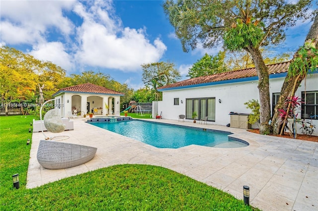 view of swimming pool with an outbuilding, a yard, and a patio