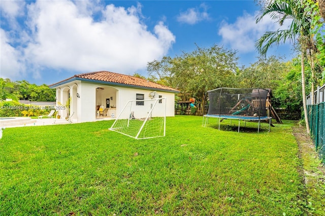 back of property with a yard, a playground, and a trampoline