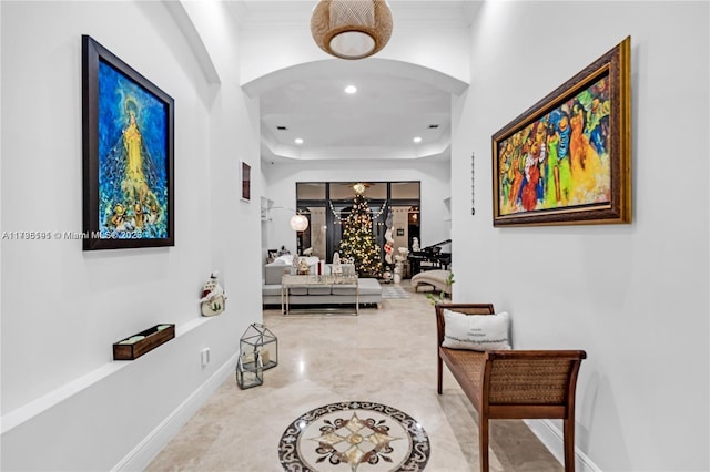 hallway with ornamental molding and a tray ceiling