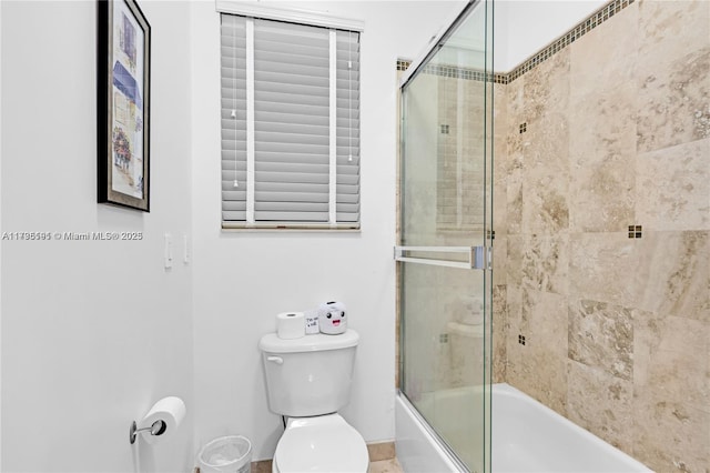 bathroom with toilet and combined bath / shower with glass door