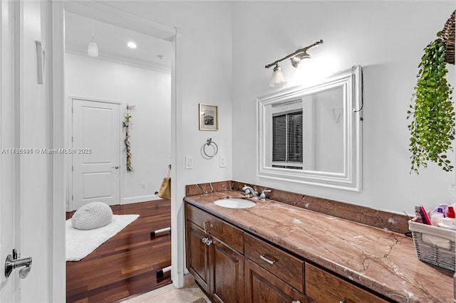 bathroom featuring hardwood / wood-style flooring, ornamental molding, and vanity