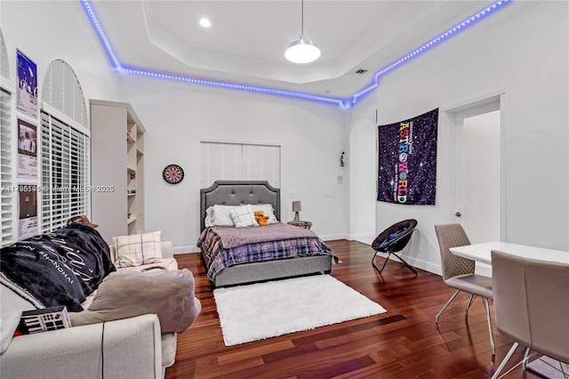 bedroom featuring dark hardwood / wood-style flooring, a tray ceiling, and crown molding