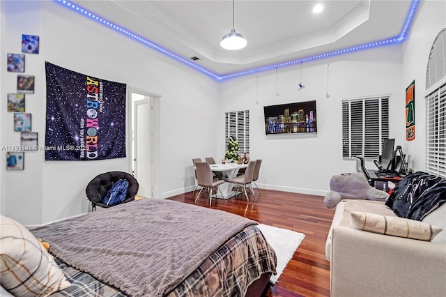 bedroom with hardwood / wood-style flooring, ornamental molding, and a tray ceiling