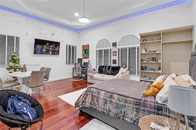 bedroom with crown molding, hardwood / wood-style flooring, and a raised ceiling