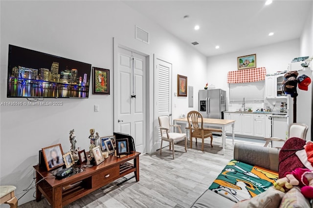 living room with sink, electric panel, and light hardwood / wood-style floors