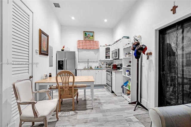 interior space with white cabinetry, stainless steel appliances, sink, and light wood-type flooring