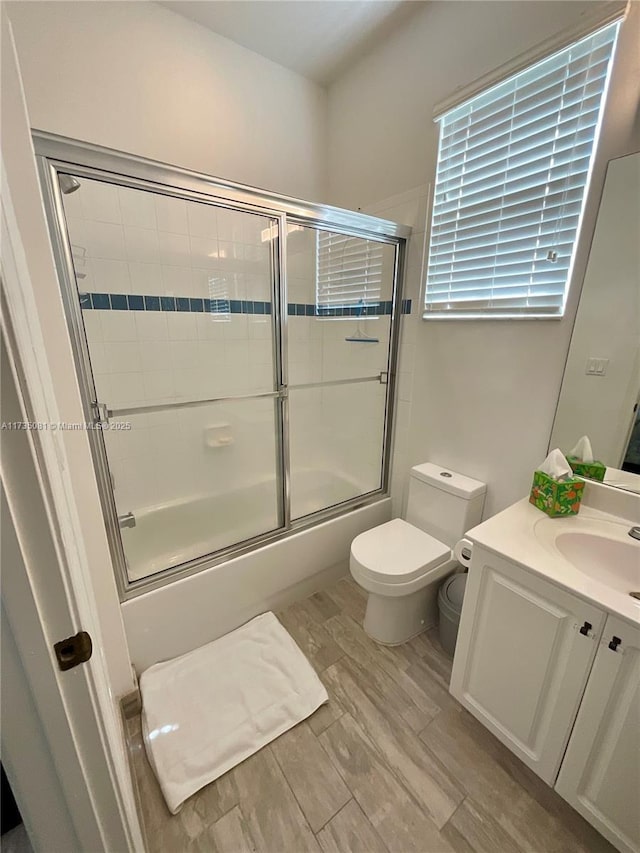 full bathroom featuring vanity, combined bath / shower with glass door, and toilet