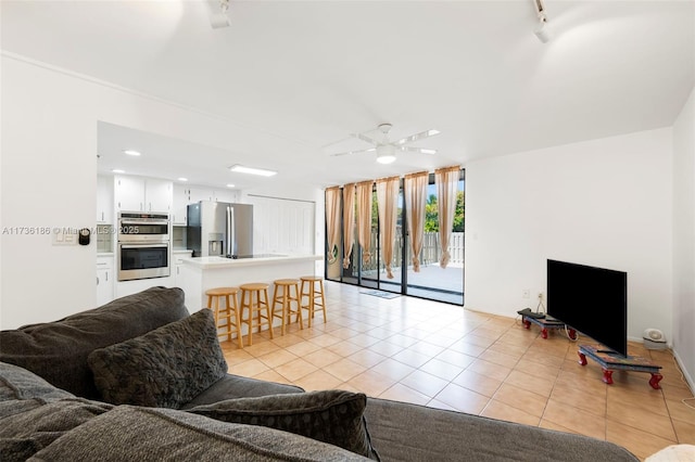 tiled living room with track lighting, expansive windows, and ceiling fan