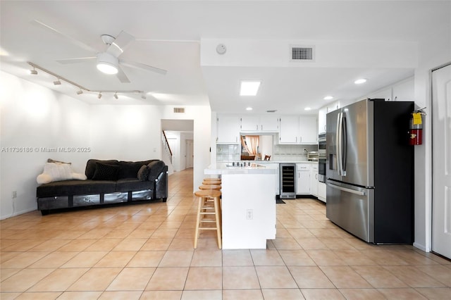 kitchen featuring light tile patterned flooring, white cabinetry, stainless steel fridge with ice dispenser, a kitchen breakfast bar, and beverage cooler