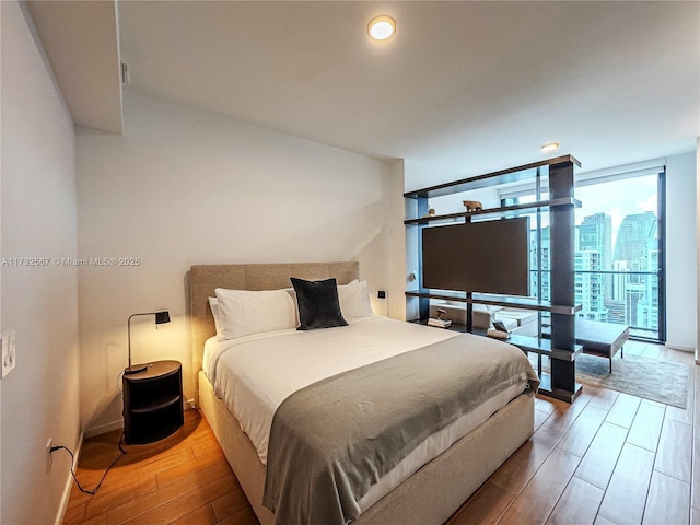 bedroom featuring expansive windows and hardwood / wood-style floors