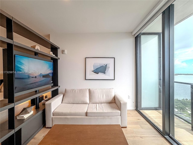 living room featuring a water view, a wall of windows, and light hardwood / wood-style floors