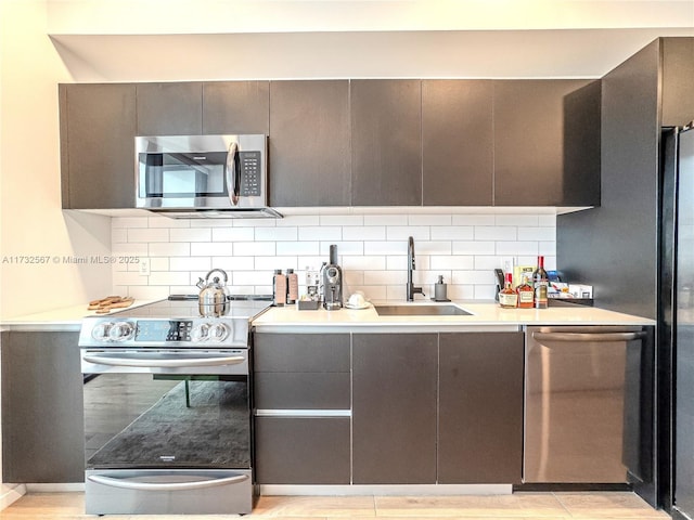 kitchen with tasteful backsplash, sink, and appliances with stainless steel finishes