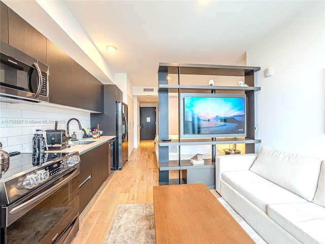 kitchen featuring sink, decorative backsplash, light hardwood / wood-style floors, and appliances with stainless steel finishes