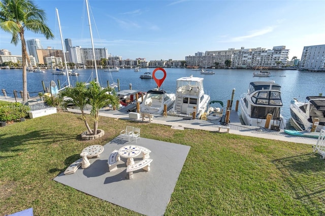 dock area with a city view, a lawn, and a water view