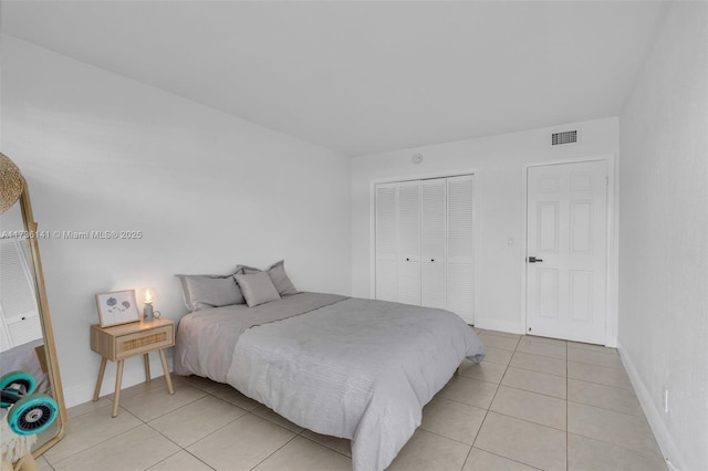 bedroom with light tile patterned floors, visible vents, baseboards, and a closet