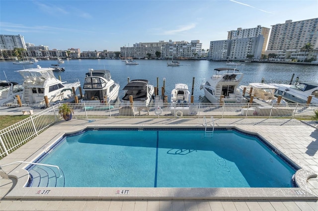 pool featuring a city view, a patio area, fence, and a water view