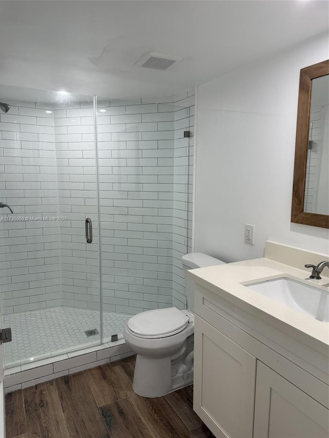 bathroom with vanity, hardwood / wood-style flooring, a shower with door, and toilet