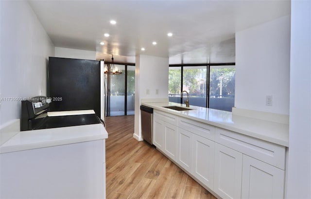 kitchen with range, freestanding refrigerator, a sink, light wood-type flooring, and stainless steel dishwasher