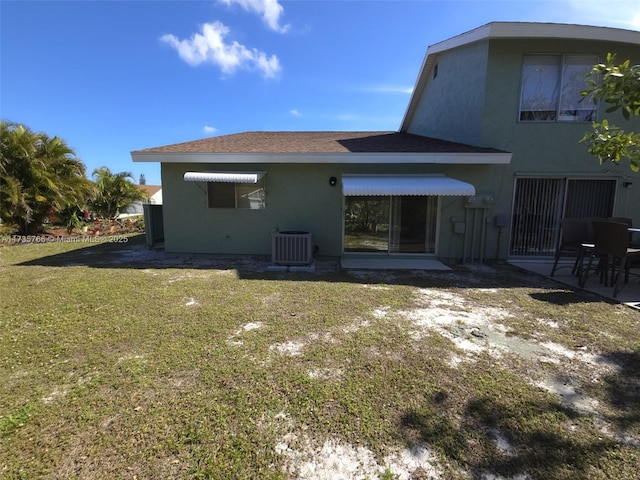 back of property featuring a lawn and central air condition unit