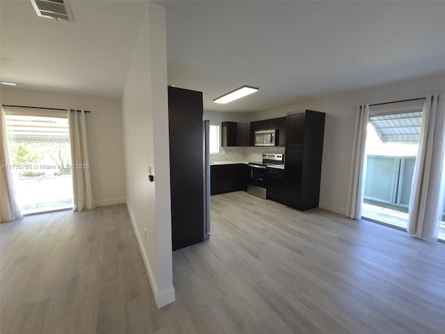 kitchen with appliances with stainless steel finishes, backsplash, and light hardwood / wood-style floors