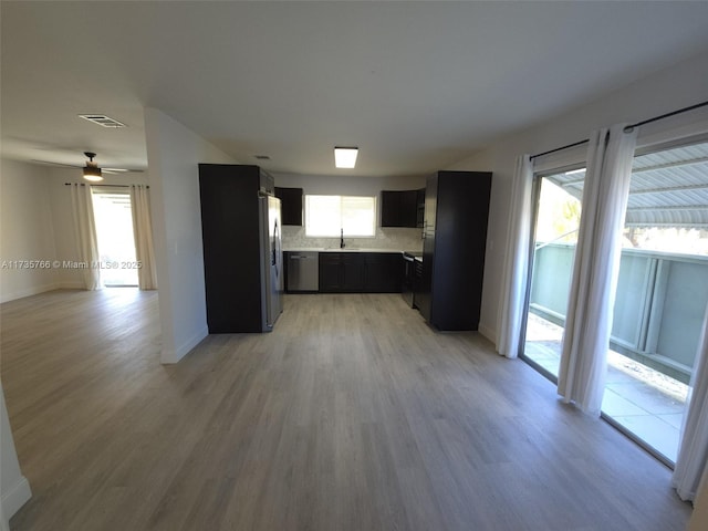 kitchen featuring decorative backsplash, stainless steel appliances, light hardwood / wood-style floors, and a healthy amount of sunlight