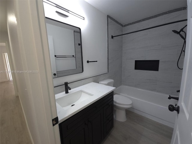 full bathroom with tiled shower / bath combo, vanity, wood-type flooring, and toilet