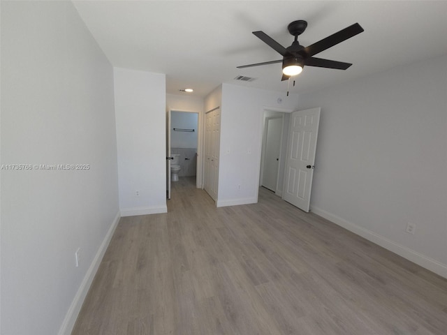 unfurnished bedroom featuring connected bathroom, light hardwood / wood-style flooring, a closet, and ceiling fan