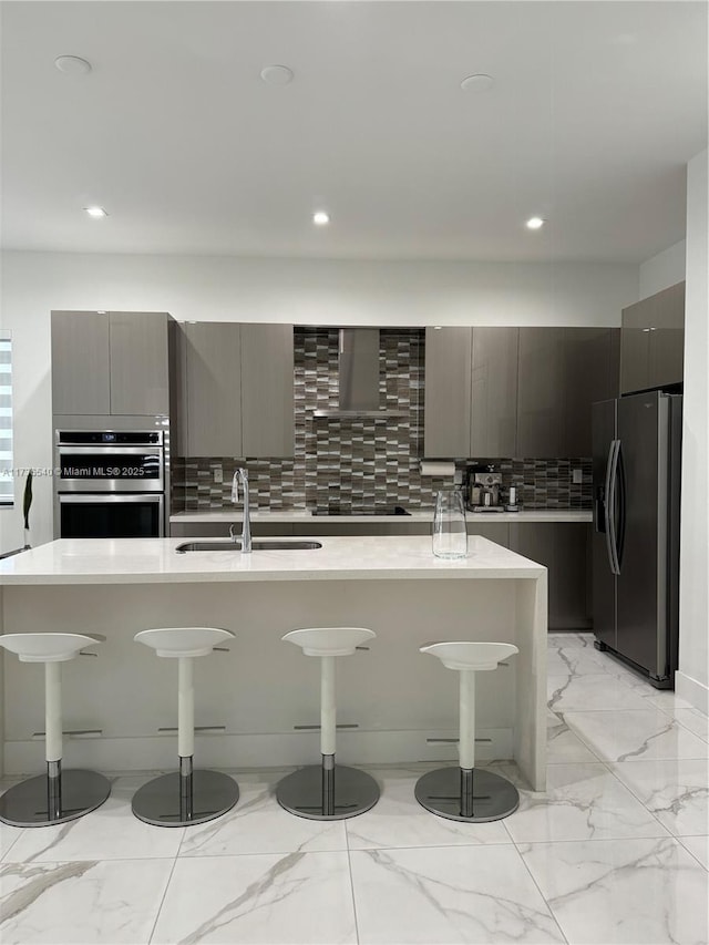 kitchen featuring sink, a breakfast bar area, gray cabinetry, stainless steel appliances, and an island with sink