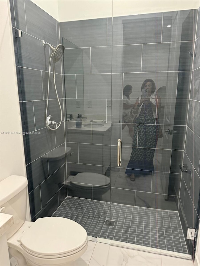 bathroom featuring a shower with door and toilet