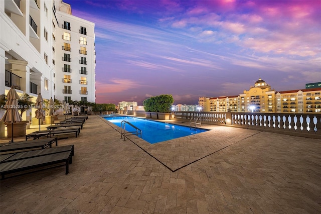 pool at dusk featuring a patio area