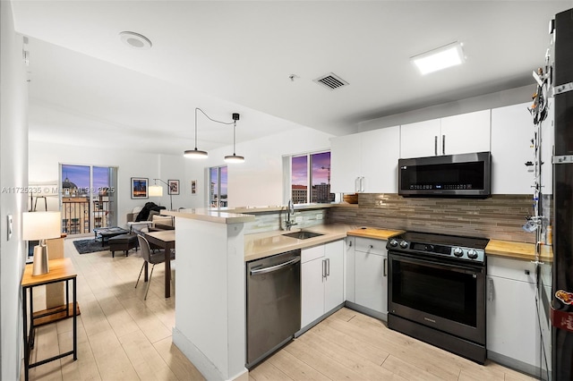 kitchen with white cabinetry, backsplash, hanging light fixtures, kitchen peninsula, and stainless steel appliances