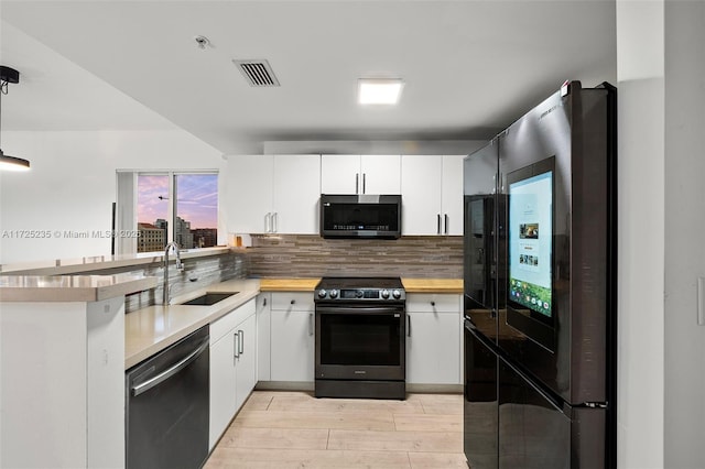 kitchen featuring sink, light hardwood / wood-style flooring, appliances with stainless steel finishes, white cabinetry, and backsplash