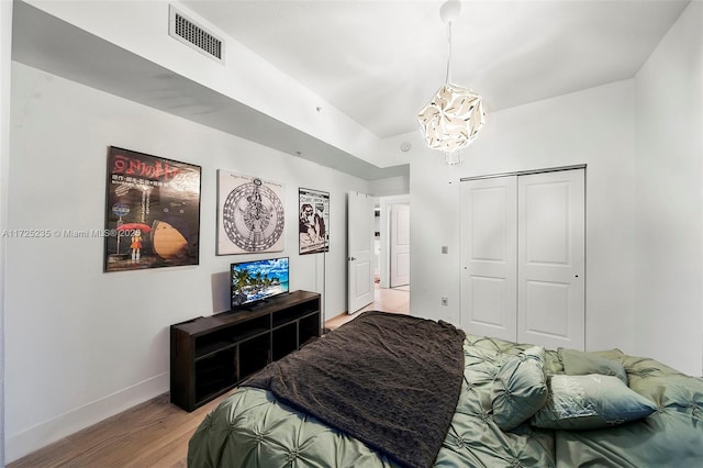 bedroom with a closet, a chandelier, and light hardwood / wood-style flooring