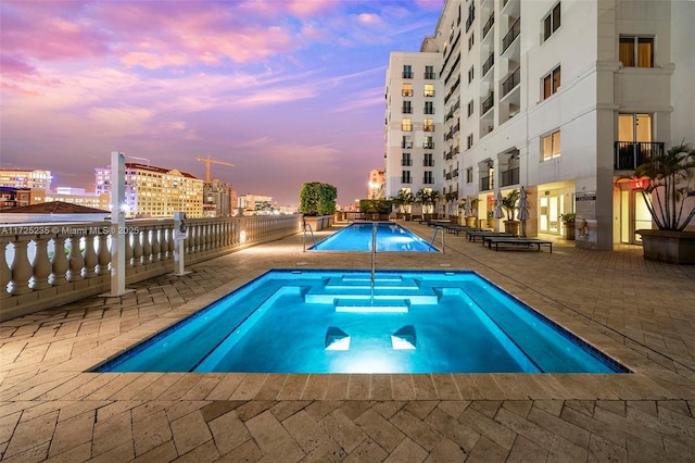 pool at dusk featuring a patio