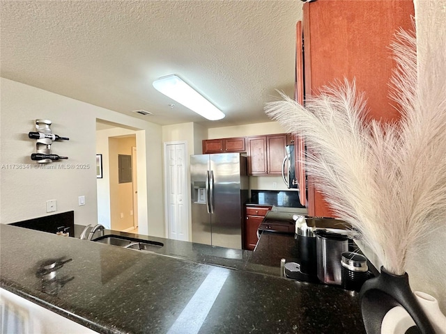 kitchen featuring appliances with stainless steel finishes, sink, a textured ceiling, and kitchen peninsula