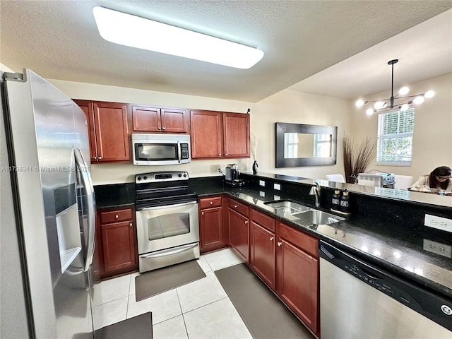 kitchen with light tile patterned flooring, appliances with stainless steel finishes, sink, and a textured ceiling