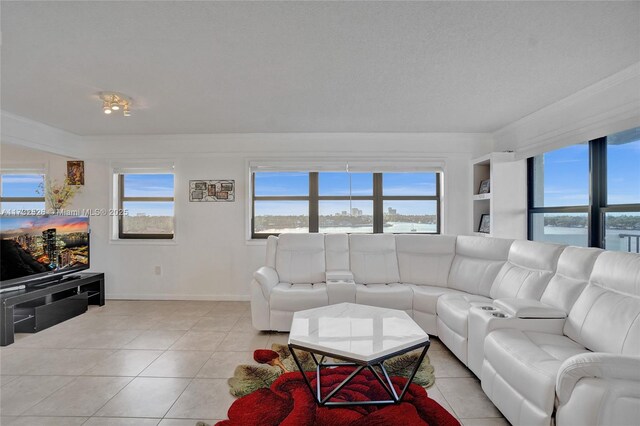 tiled living room with crown molding, a water view, a wealth of natural light, and a textured ceiling