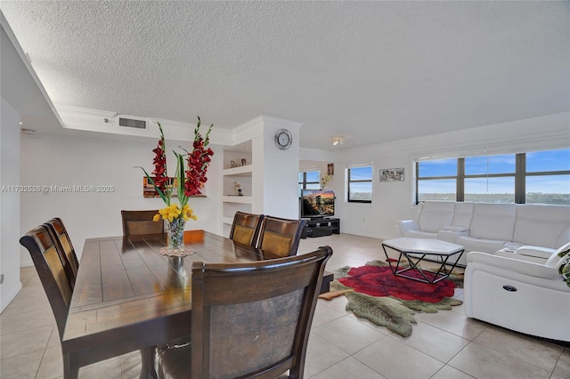 dining room featuring a textured ceiling, built in shelves, light tile patterned floors, and visible vents