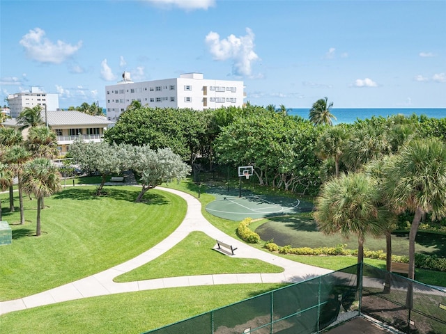 view of home's community with fence, community basketball court, a water view, and a lawn