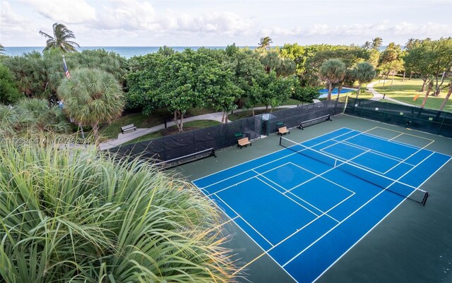 view of sport court featuring fence and a water view