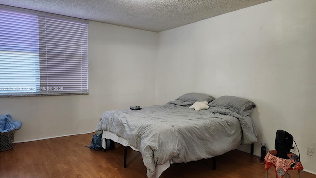 bedroom with dark hardwood / wood-style flooring and a textured ceiling