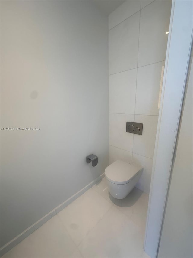 bathroom featuring tile patterned floors, toilet, and tile walls