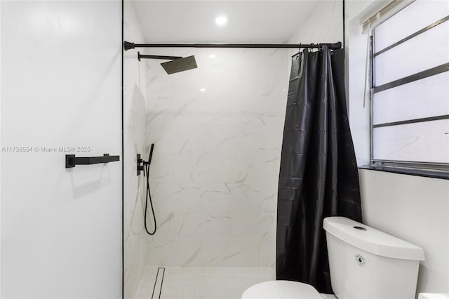 bathroom featuring toilet and a marble finish shower