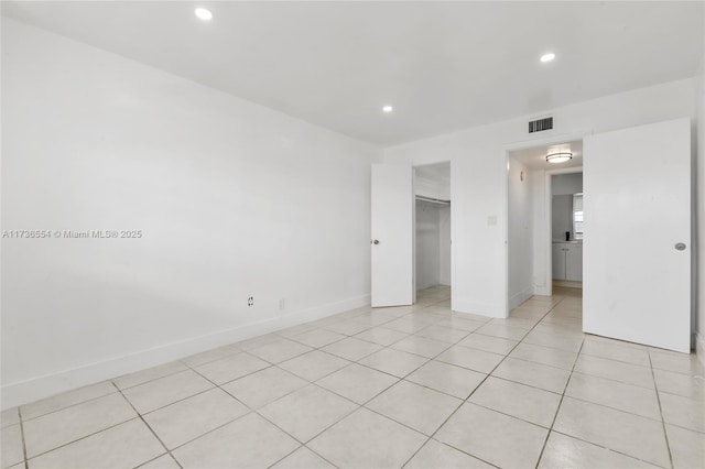 unfurnished bedroom with light tile patterned floors, recessed lighting, visible vents, a spacious closet, and baseboards