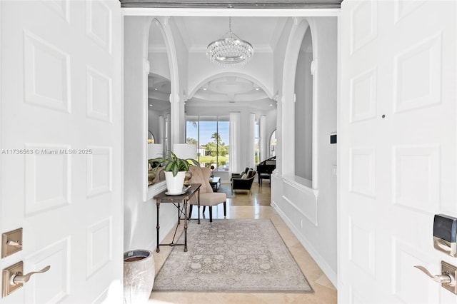 foyer featuring ornate columns, crown molding, light tile patterned floors, and a notable chandelier