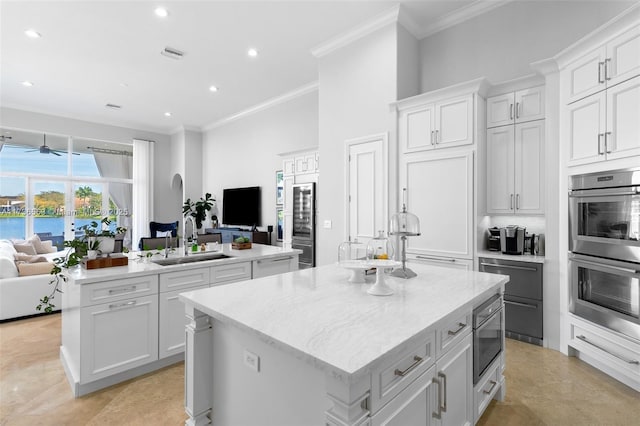 kitchen featuring sink, crown molding, white cabinetry, stainless steel appliances, and a center island