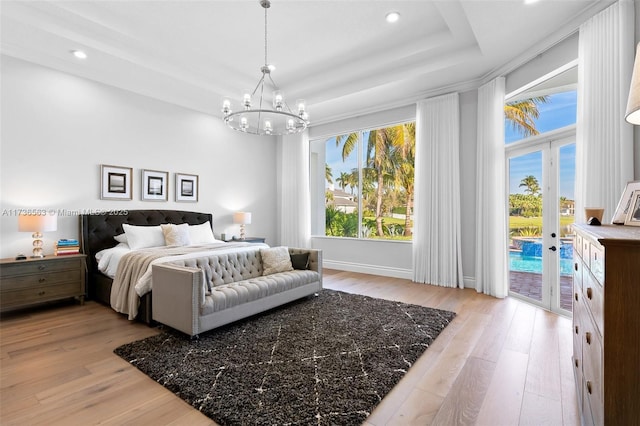 bedroom featuring a tray ceiling, access to exterior, multiple windows, and light wood-type flooring